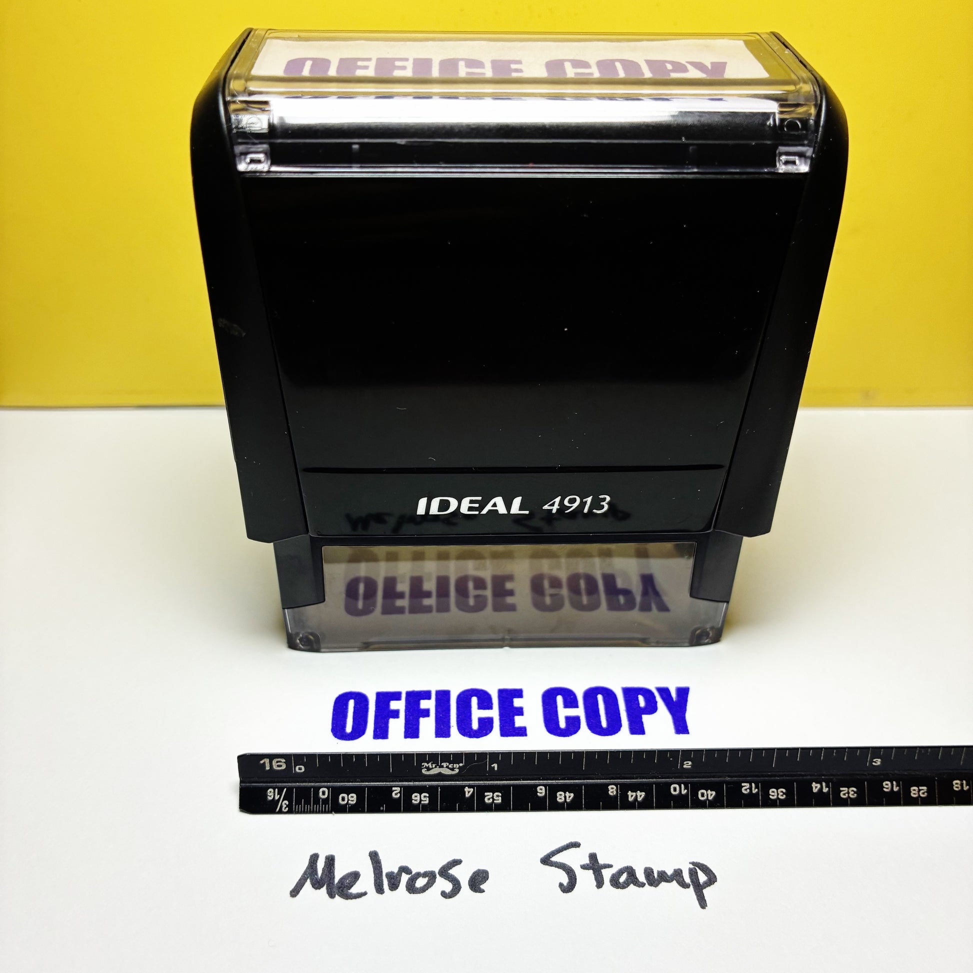 Black stamp with 'OFFICE COPY' text and a ruler for scale on a yellow background