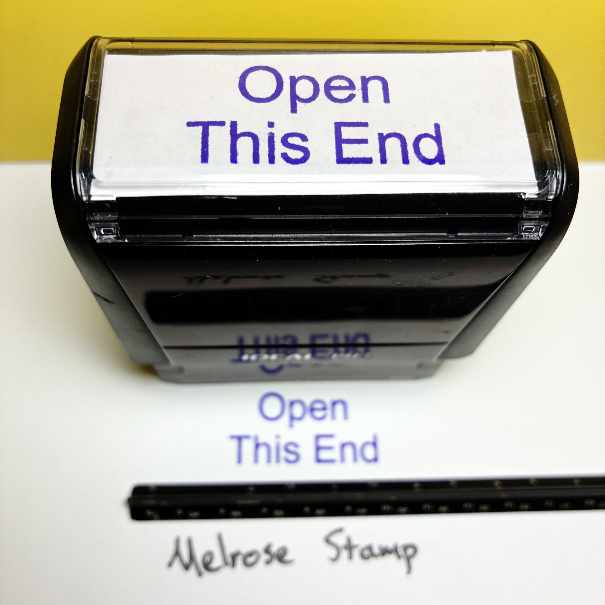 Rubber stamp with 'Open This End' text on a white background