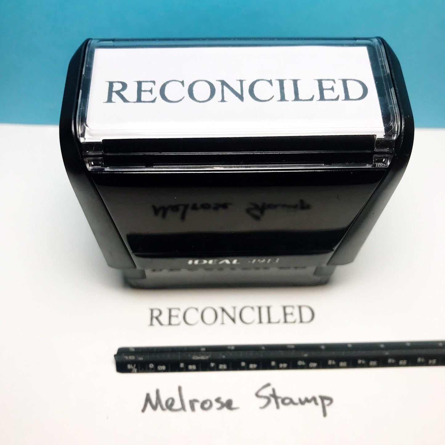 Self-inking stamp with 'RECONCILED' text on a white background