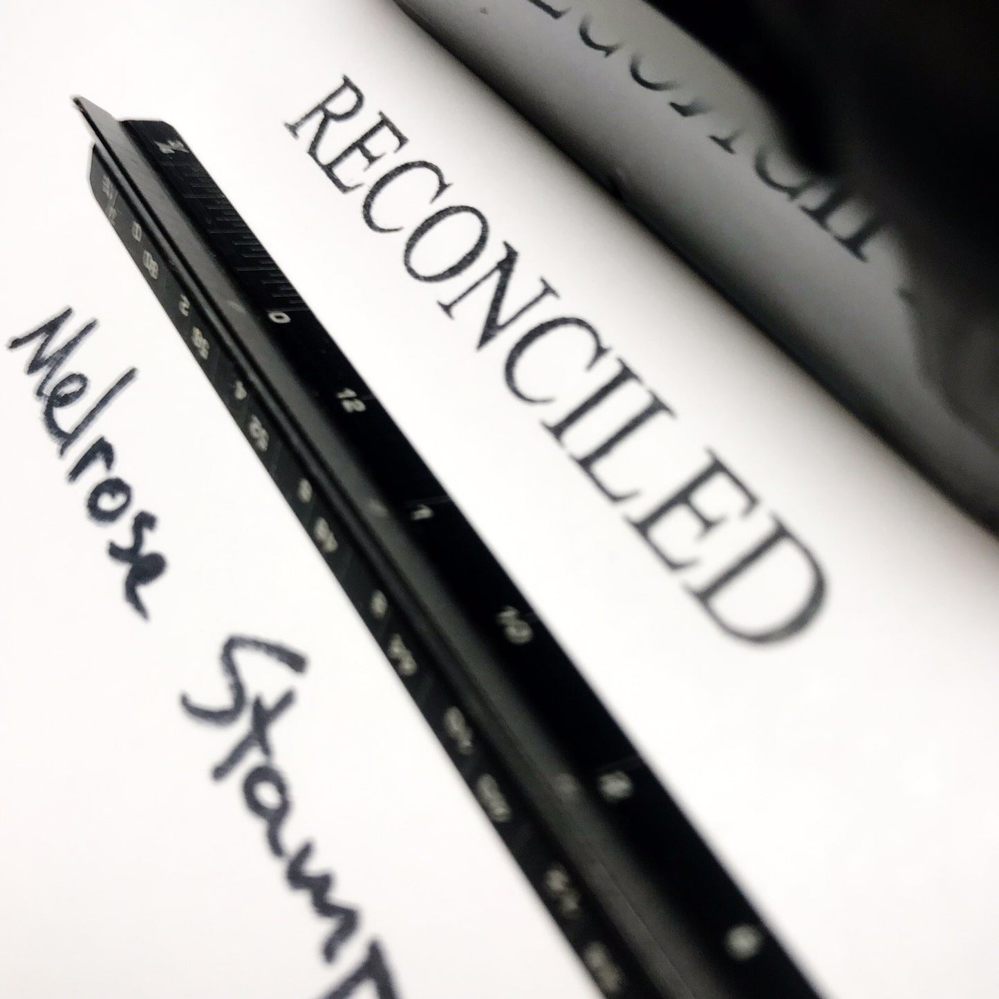 Close-up of a pen with 'RECONCILED' text on a white background