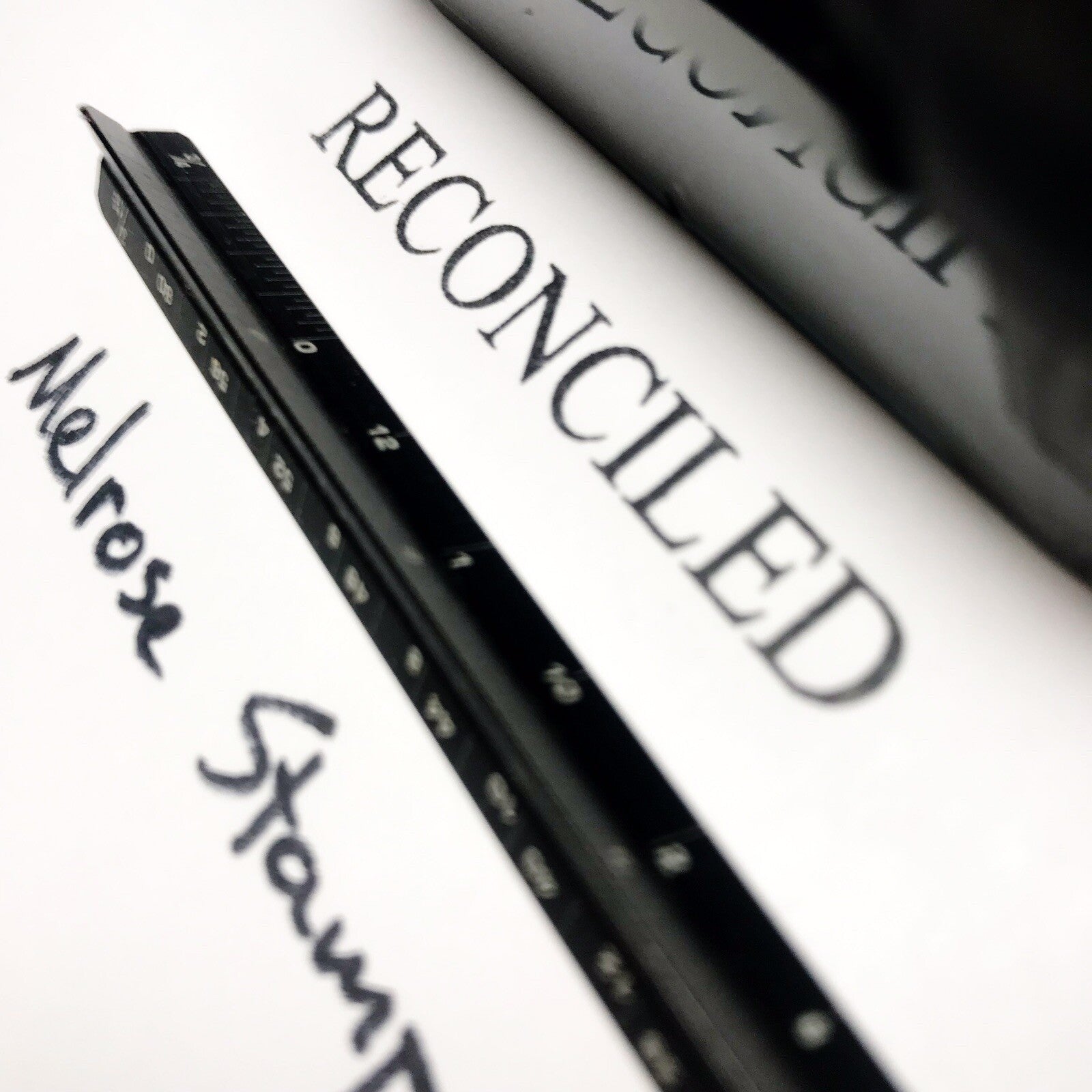 Close-up of a pen with 'RECONCILED' text on a white background