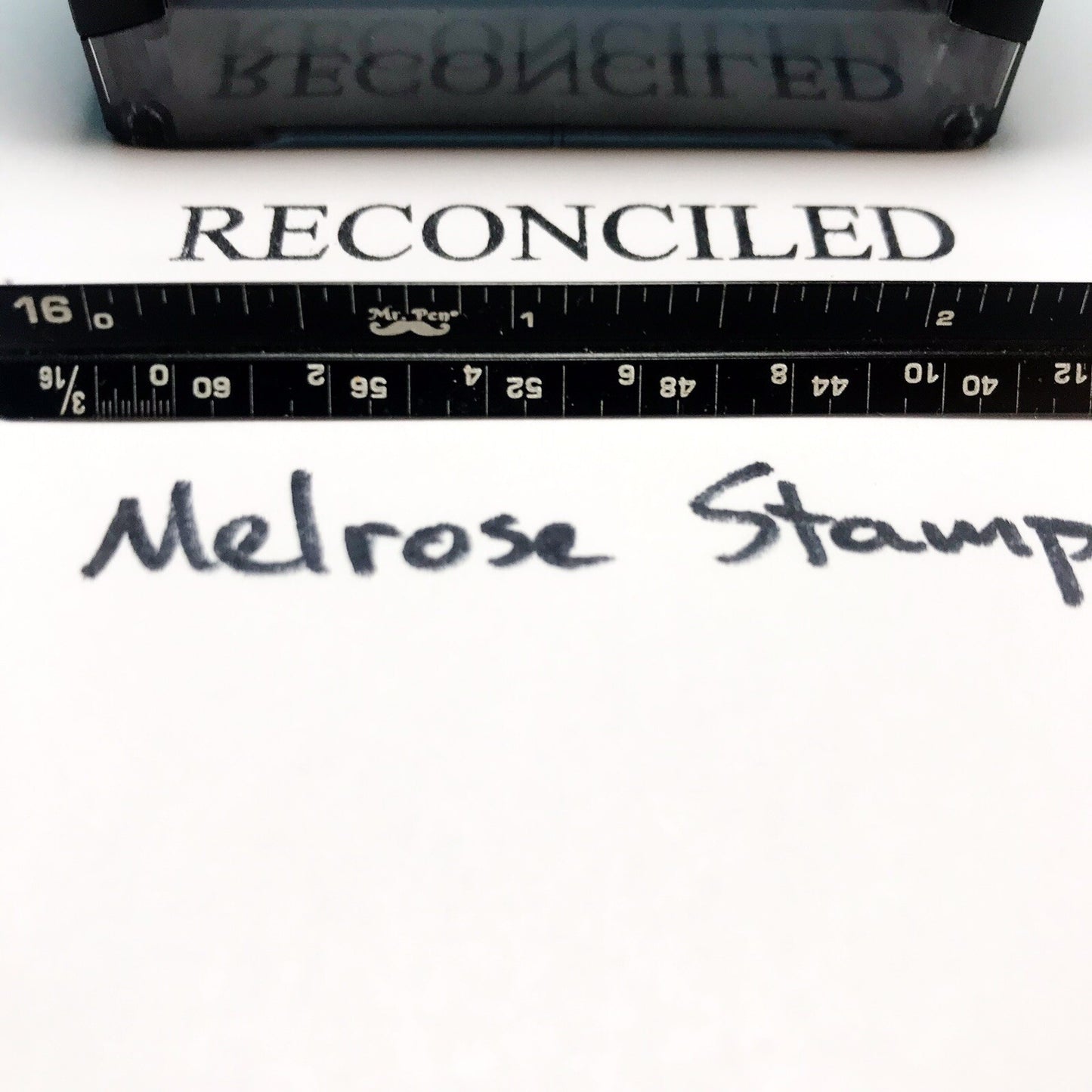 Rubber stamp with 'RECONCILED' text and a ruler below on a white background