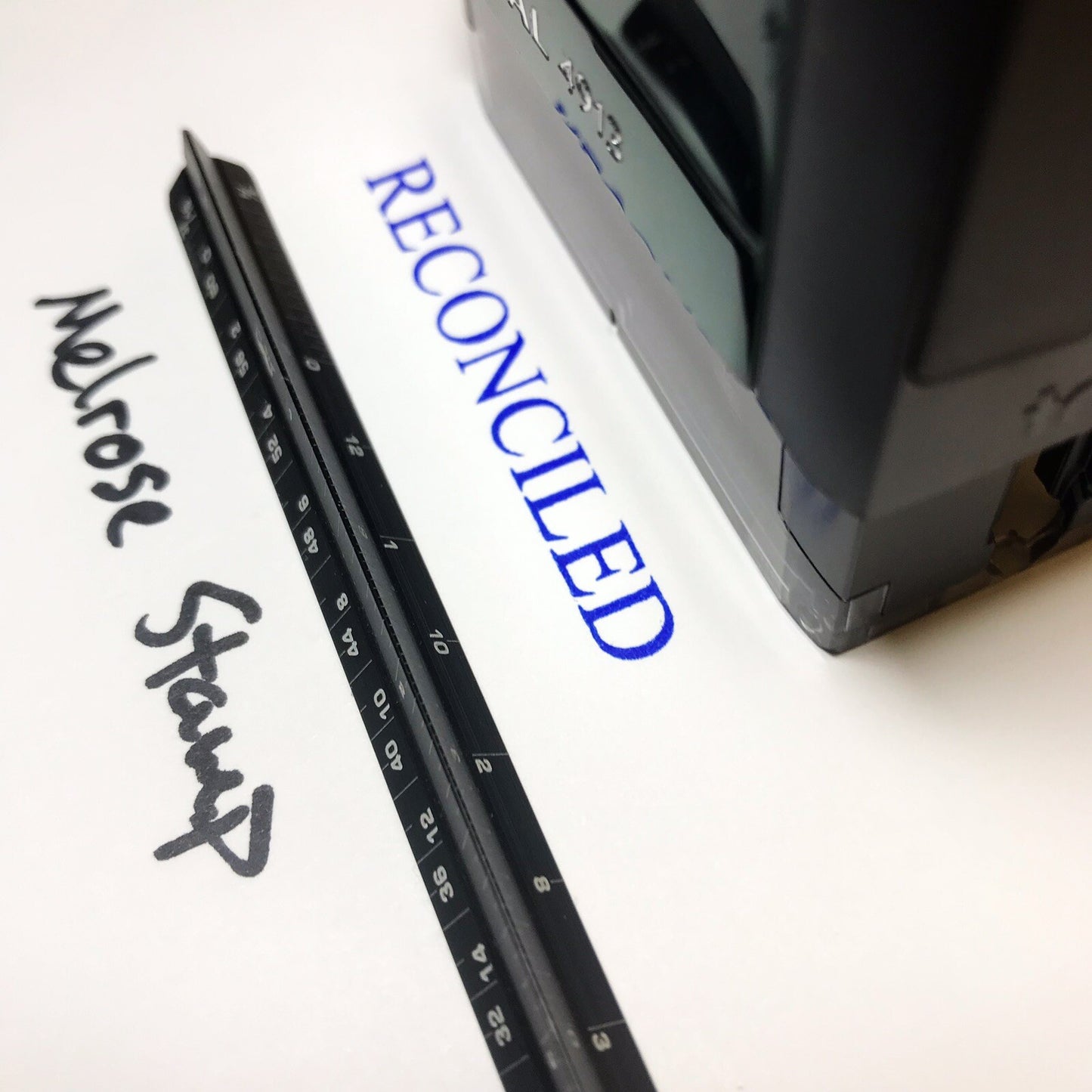 Black stamp with 'RECONCILED' text on a white background