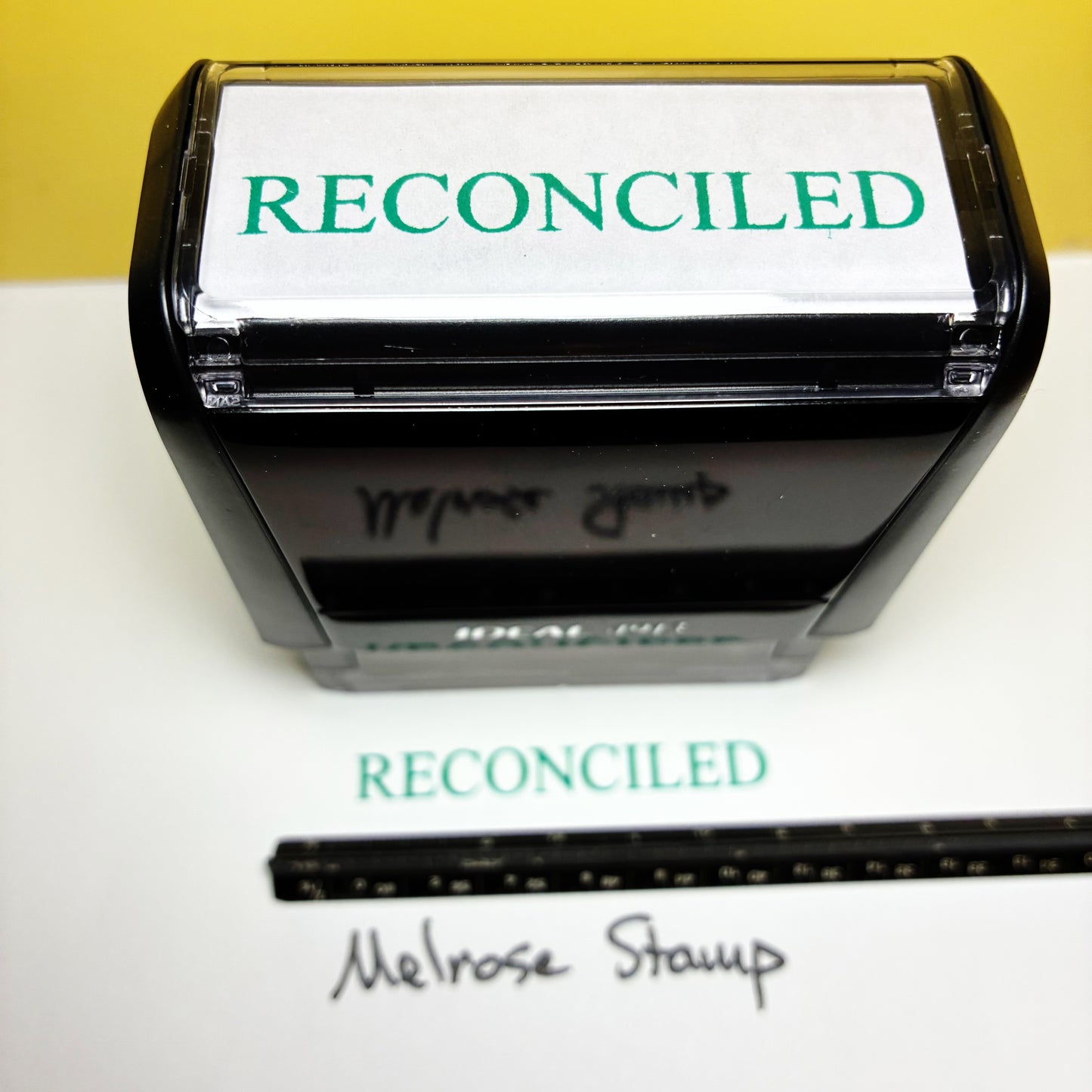 Self-inking stamp with 'RECONCILED' text on a white background