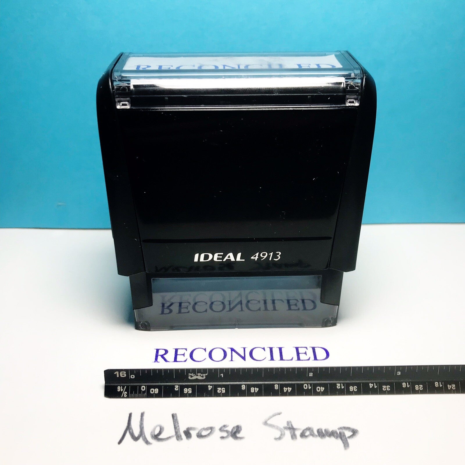 Black stamp with 'Reconciled' on a white surface with a blue background