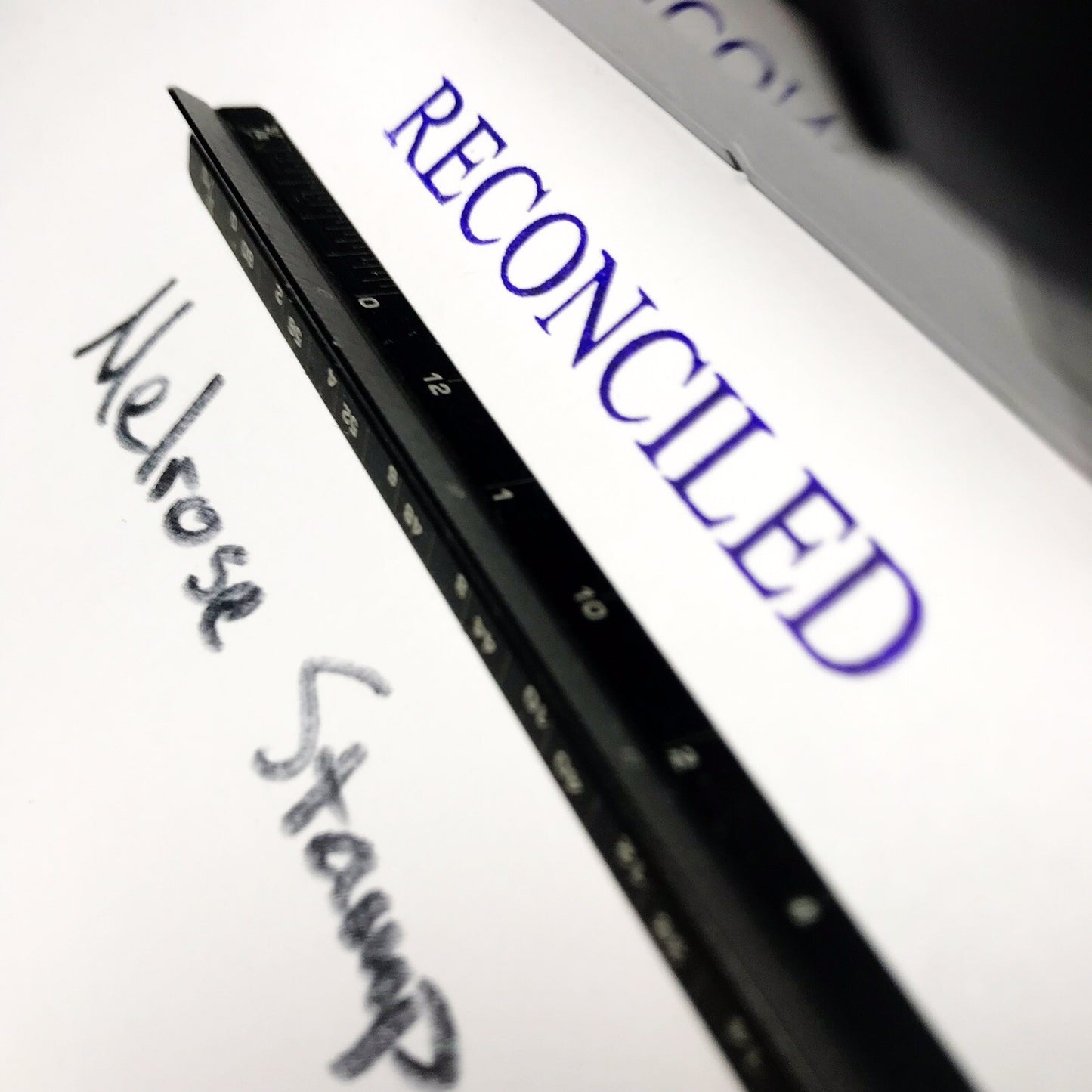 Close-up of a digital device screen displaying the word 'RECONCILED' with a stylus on a white background.