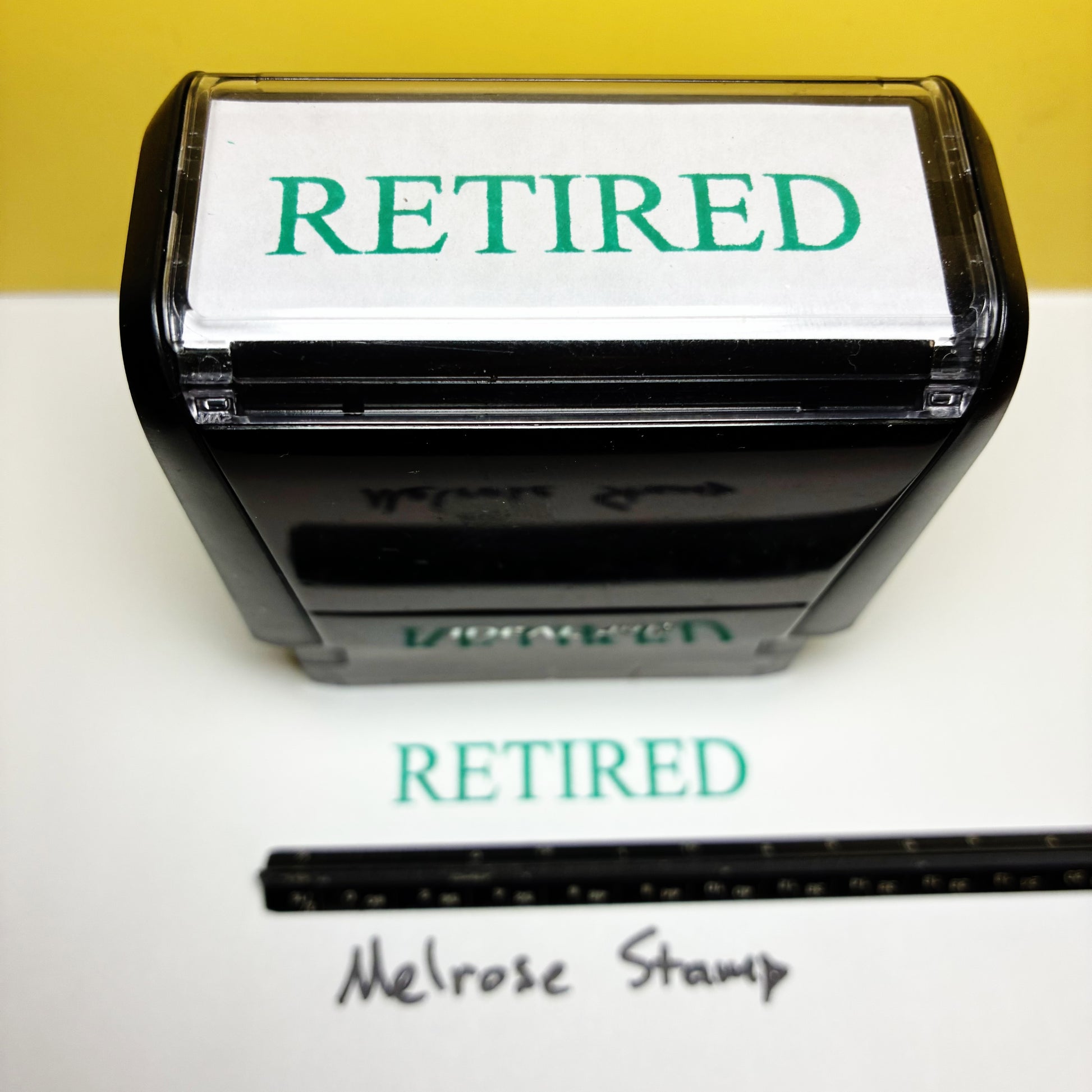Retired stamp with a ruler for size reference on a white background
