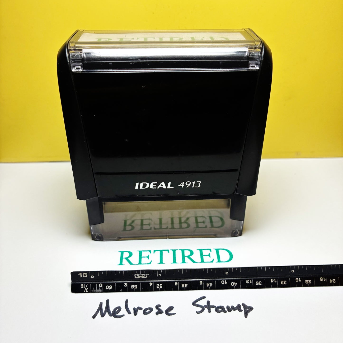 Black stamp with 'Retired' on a white surface with a yellow background