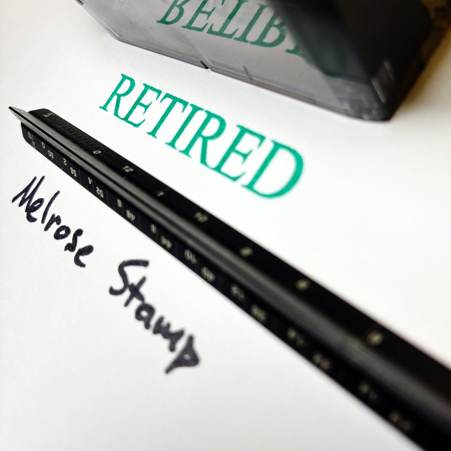 Black stamp with 'Melrose Stamp' text on a white surface, with 'RETIRED' in green above.