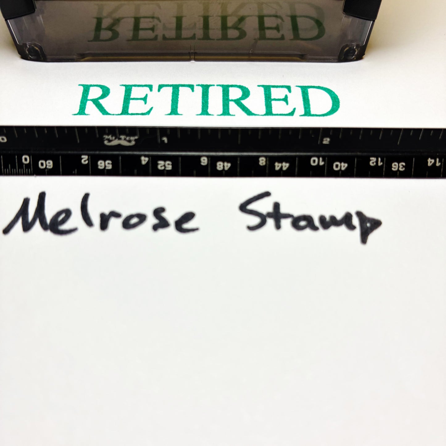 Text 'RETIRED' in green above 'Melrose Stamp' text on a white background with a ruler at the bottom.