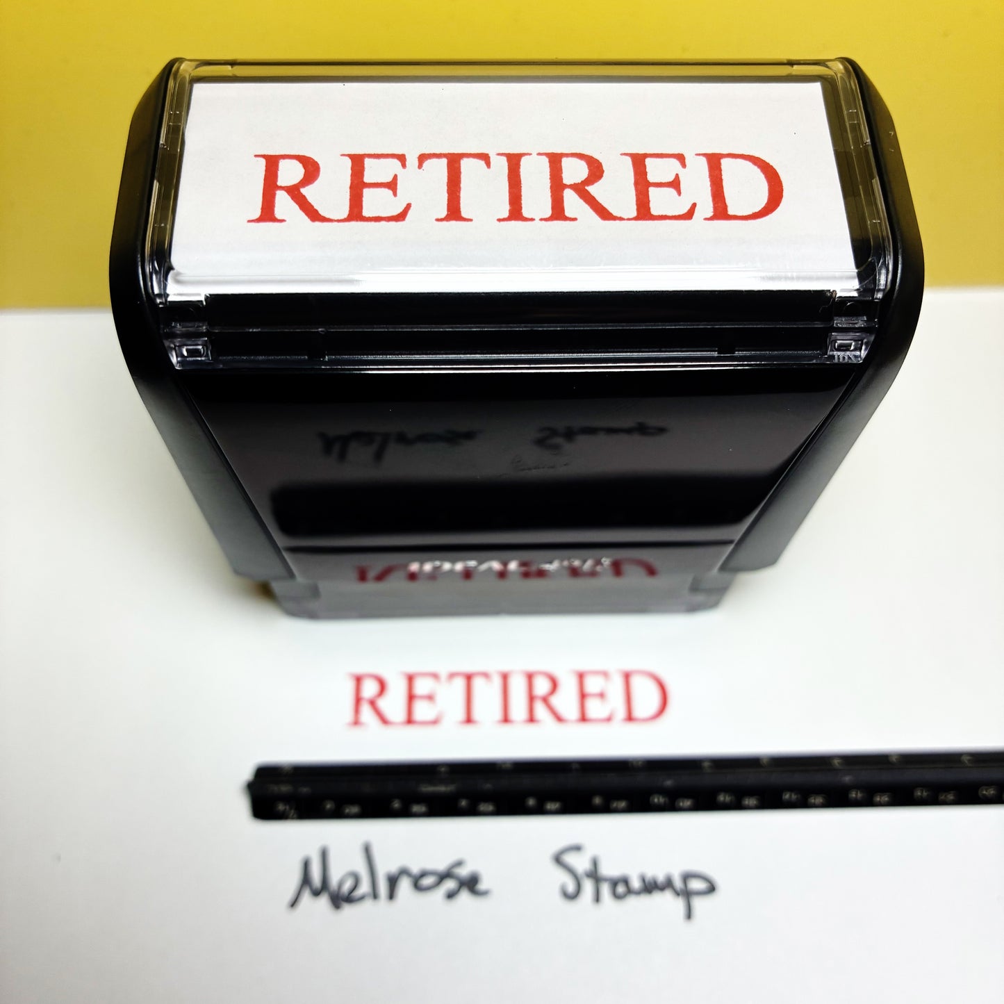 Retired stamp with a ruler for size reference on a white background