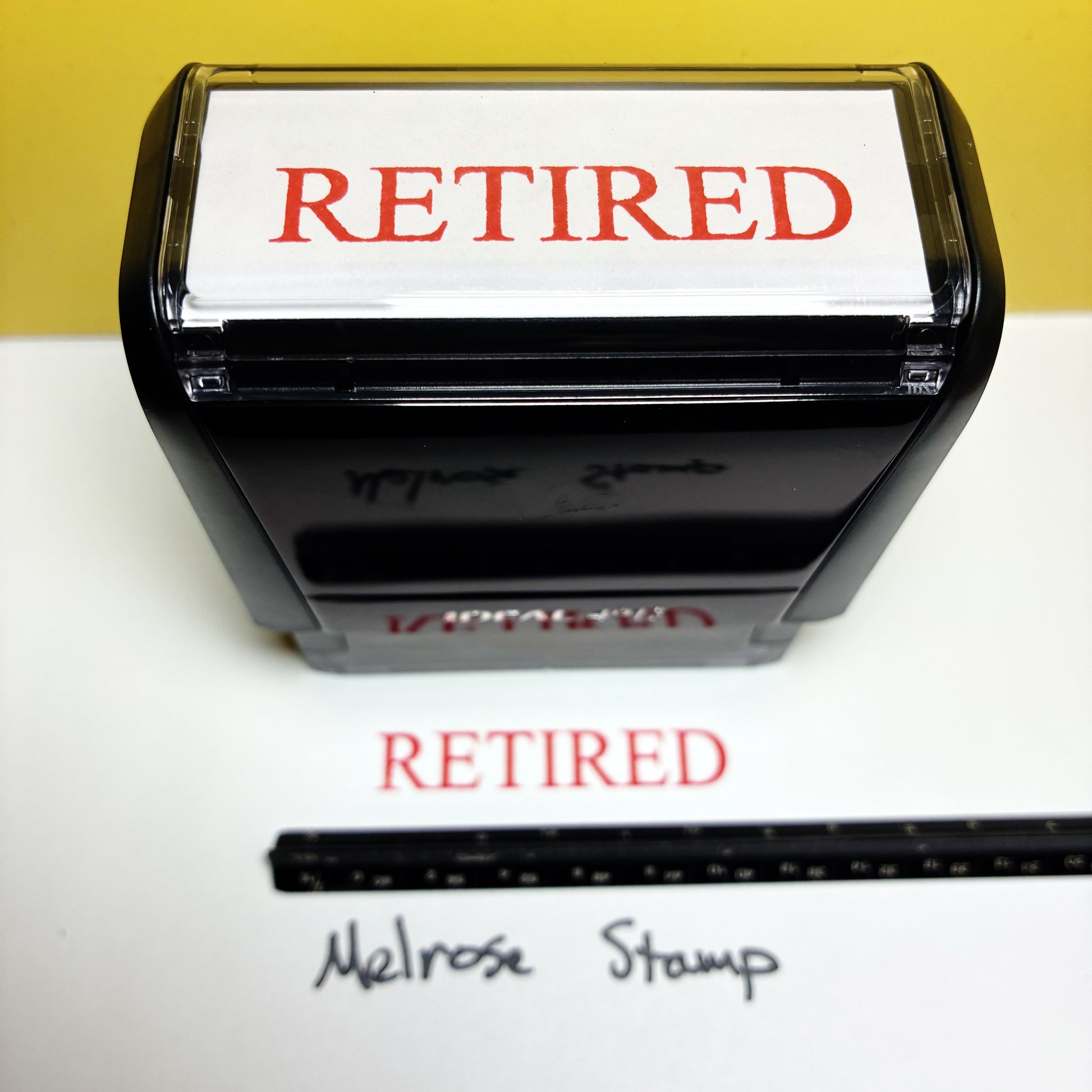 Retired stamp with a ruler for size reference on a white background