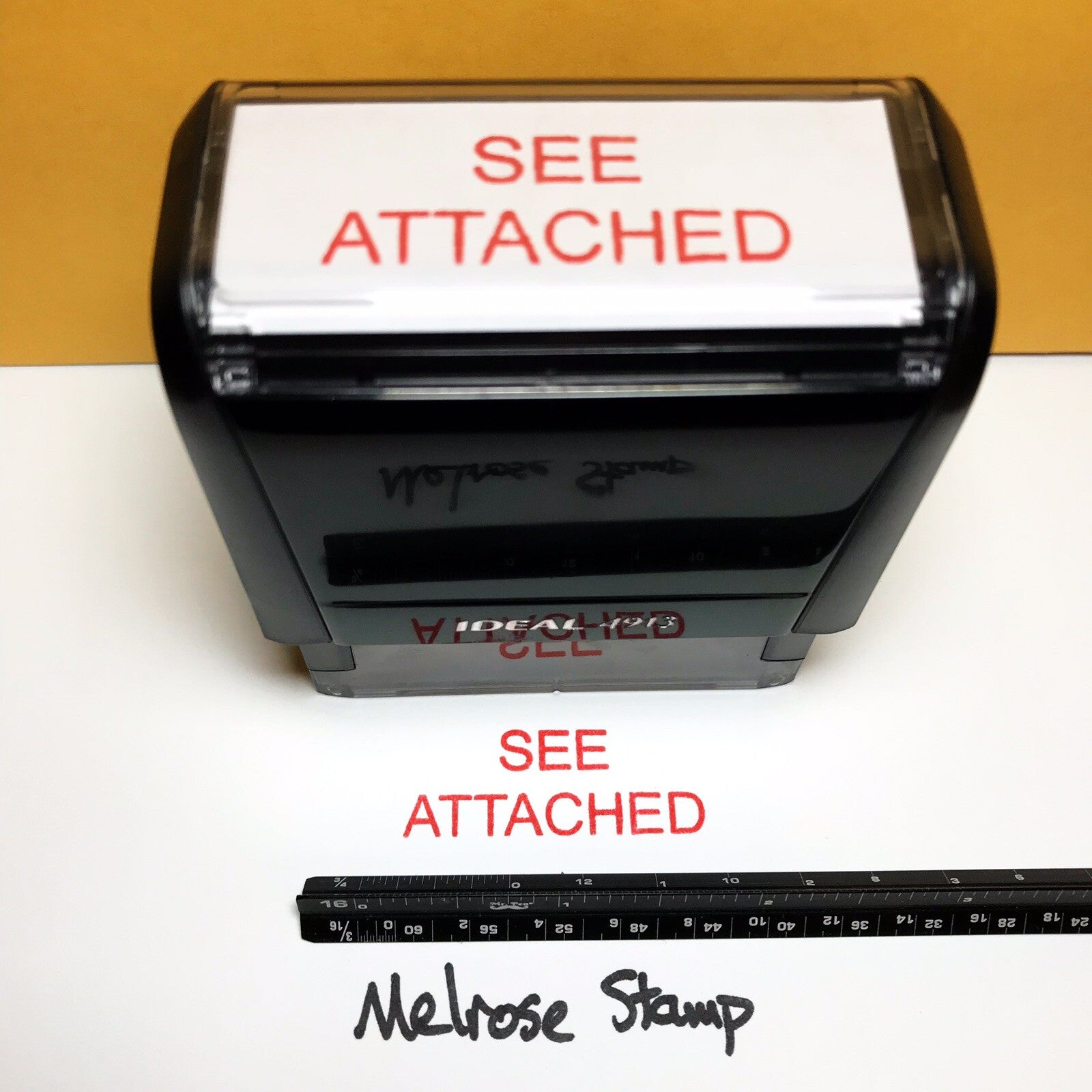 Rubber stamp with 'SEE ATTACHED' text on a white background