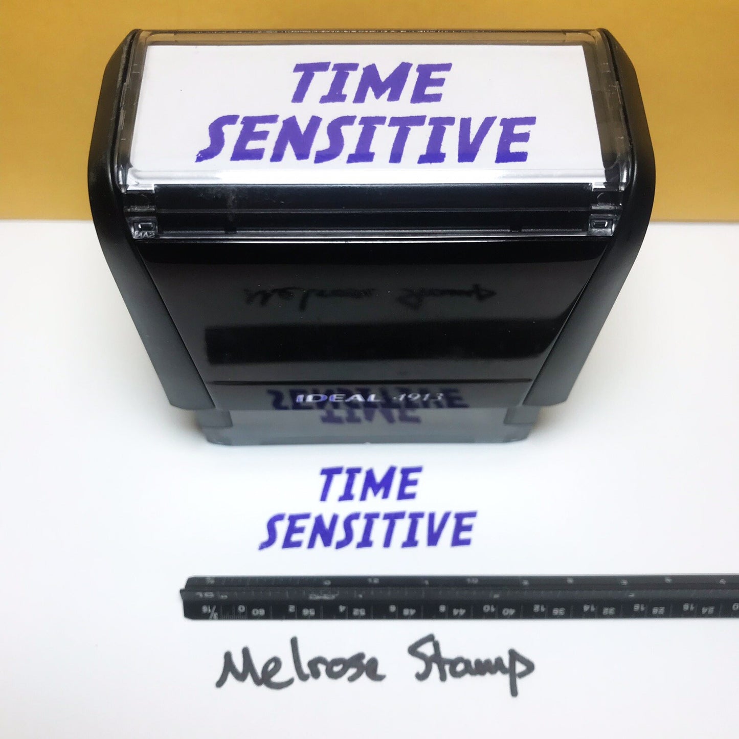 Rubber stamp with 'TIME SENSITIVE' text and a ruler below on a white background
