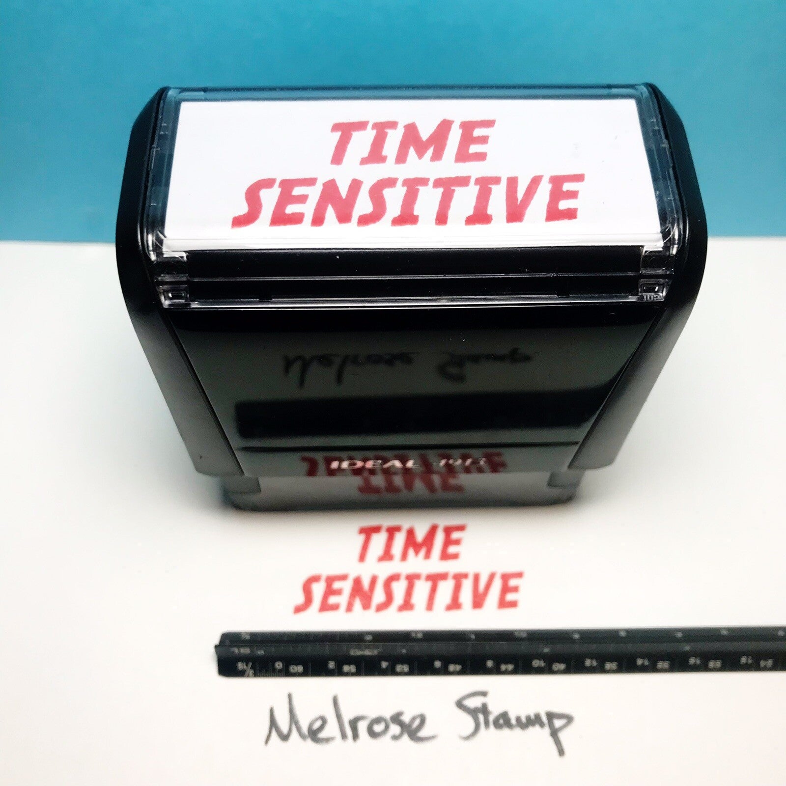 Rubber stamp with 'TIME SENSITIVE' text on a white surface with a blue background