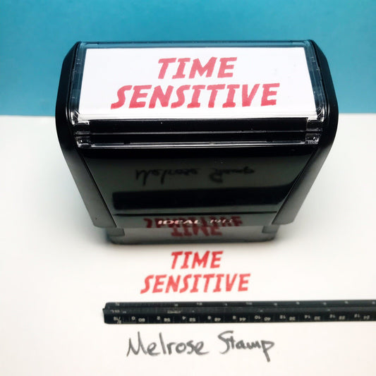 Rubber stamp with 'TIME SENSITIVE' text on a white surface with a blue background