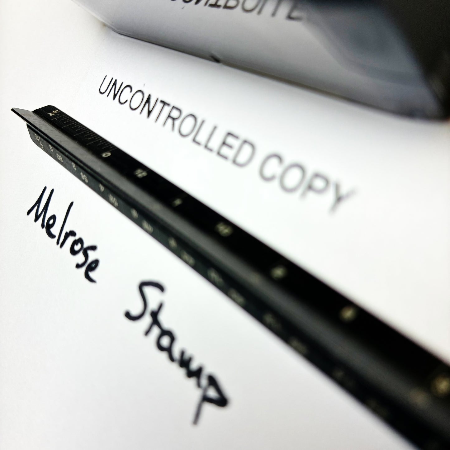 Close-up of a document with 'Melrose Stamp' and 'Uncontrolled Copy' text.