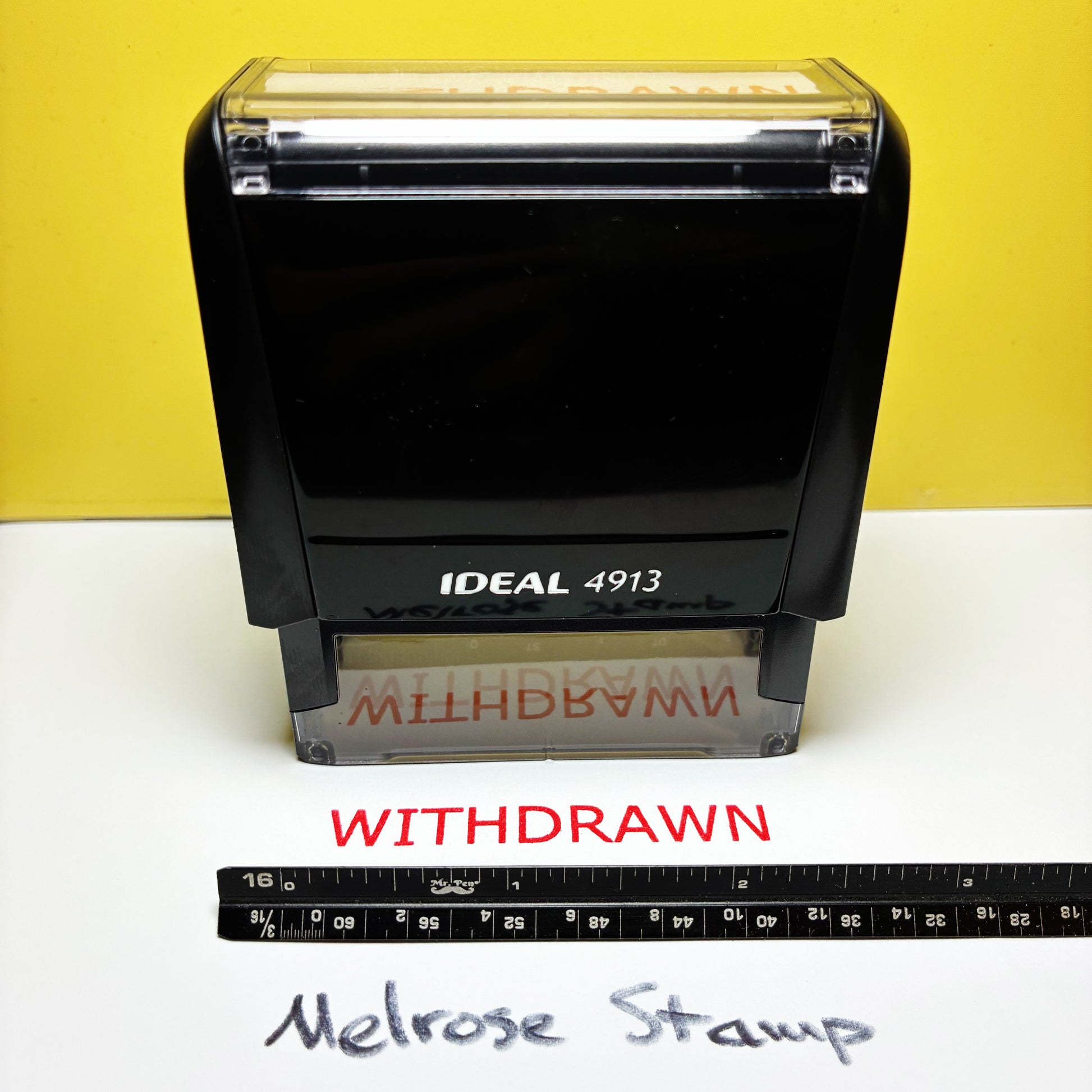 Rubber stamp with 'WITHDRAWN' text on a white surface against a yellow background